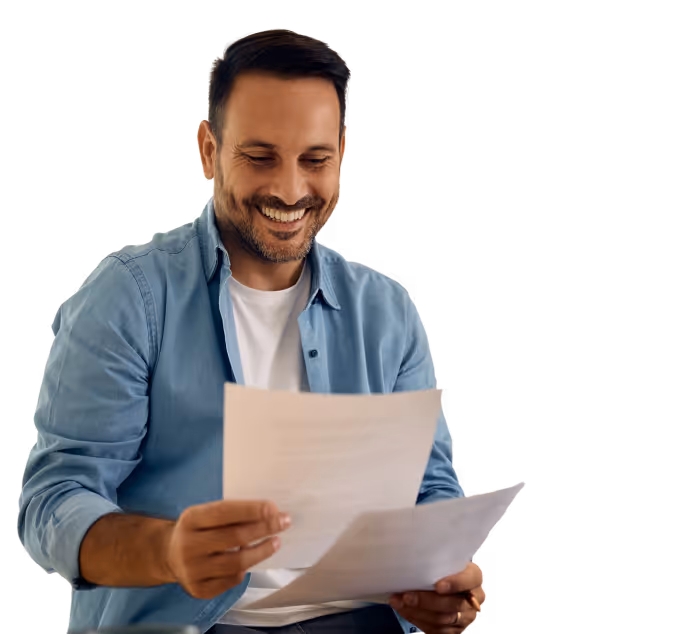 Smiling man in a blue shirt holding and reading documents.