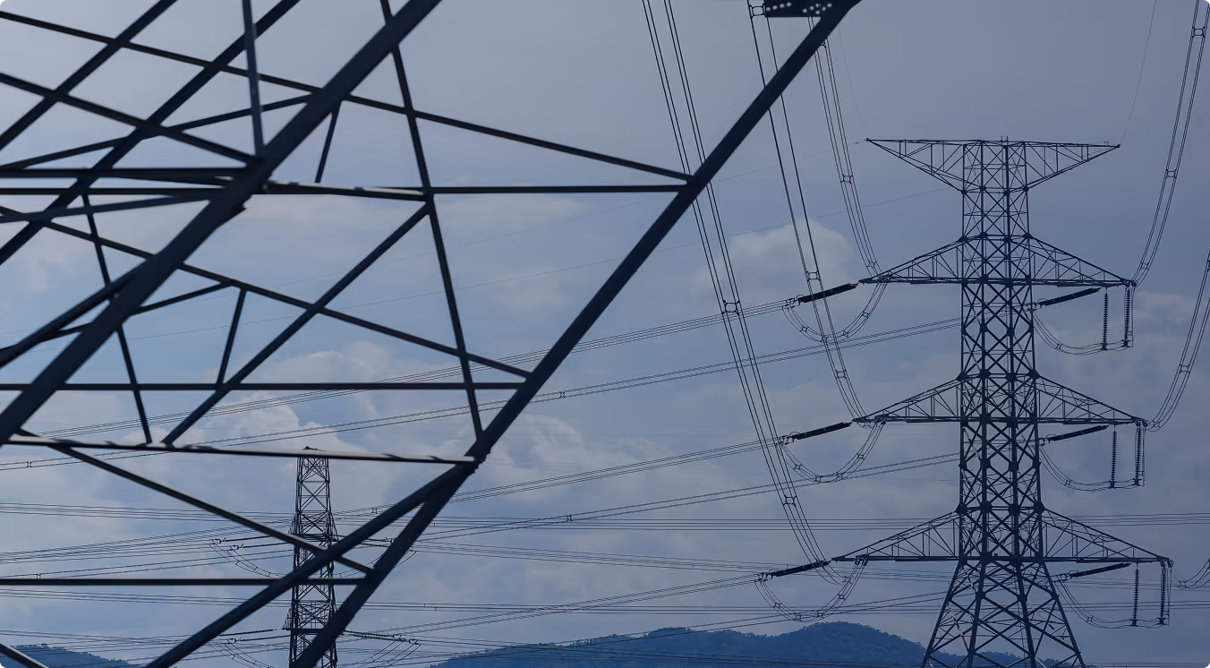 High voltage electricity transmission towers with power lines against a partly cloudy sky.