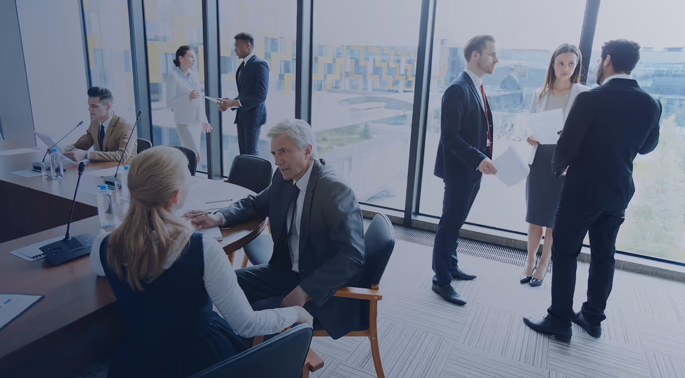 Business professionals in suits having discussions in a modern office with large windows.