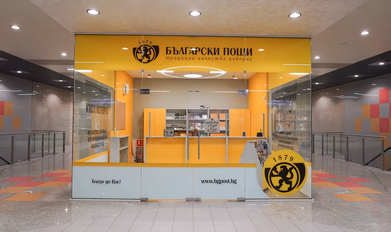 Interior of a Bulgarian Post office with bright yellow counters and glass walls in a modern building.