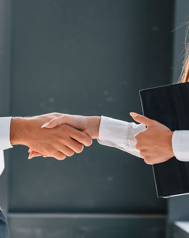 Two people shaking hands, one giving a thumbs-up while holding a black folder.