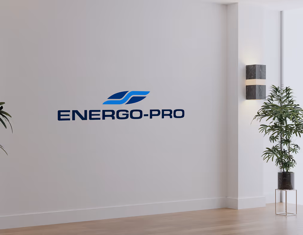 Modern office interior with a white wall featuring the Energo-Pro logo in blue, next to a potted plant and wall light fixture.