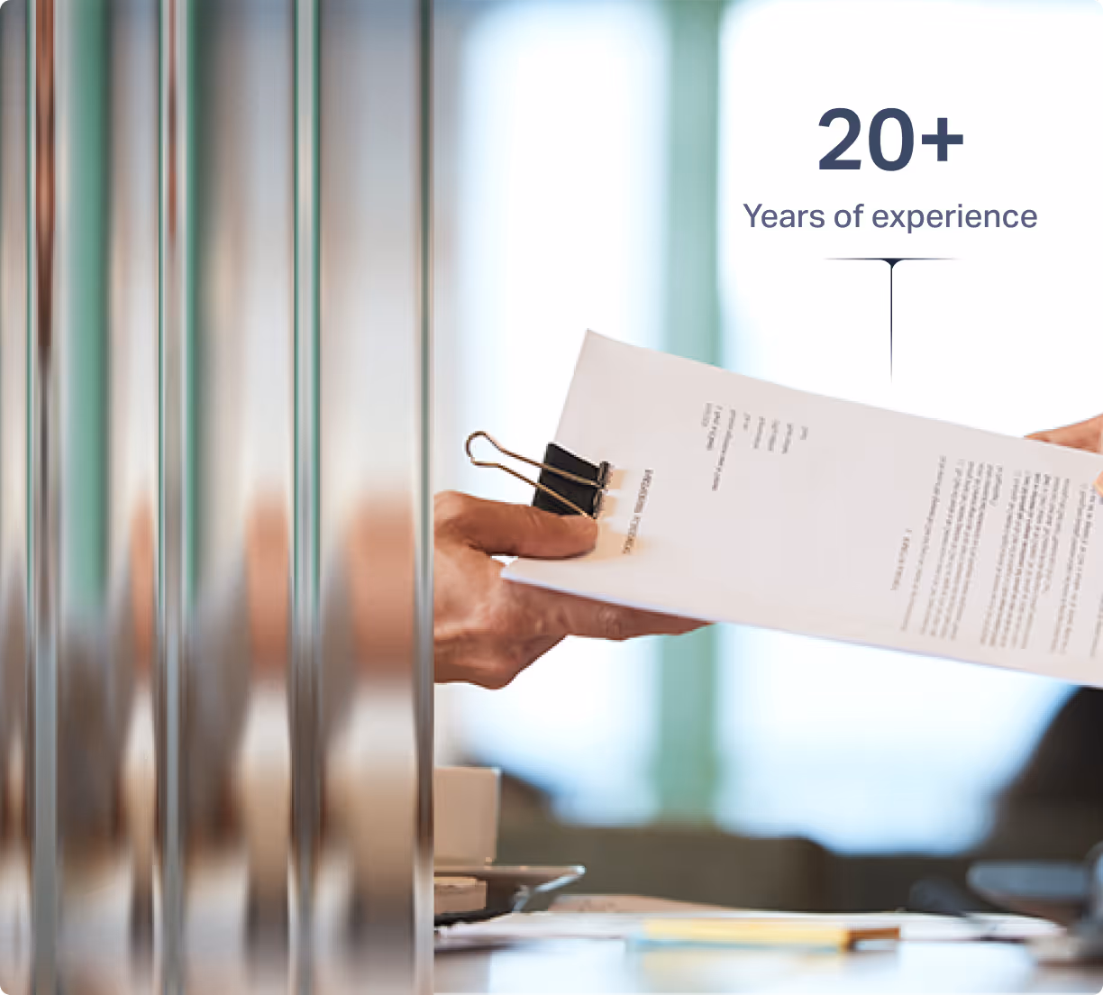 Две ръце си подават документ с текст и щипка за хартия на офисна маса.