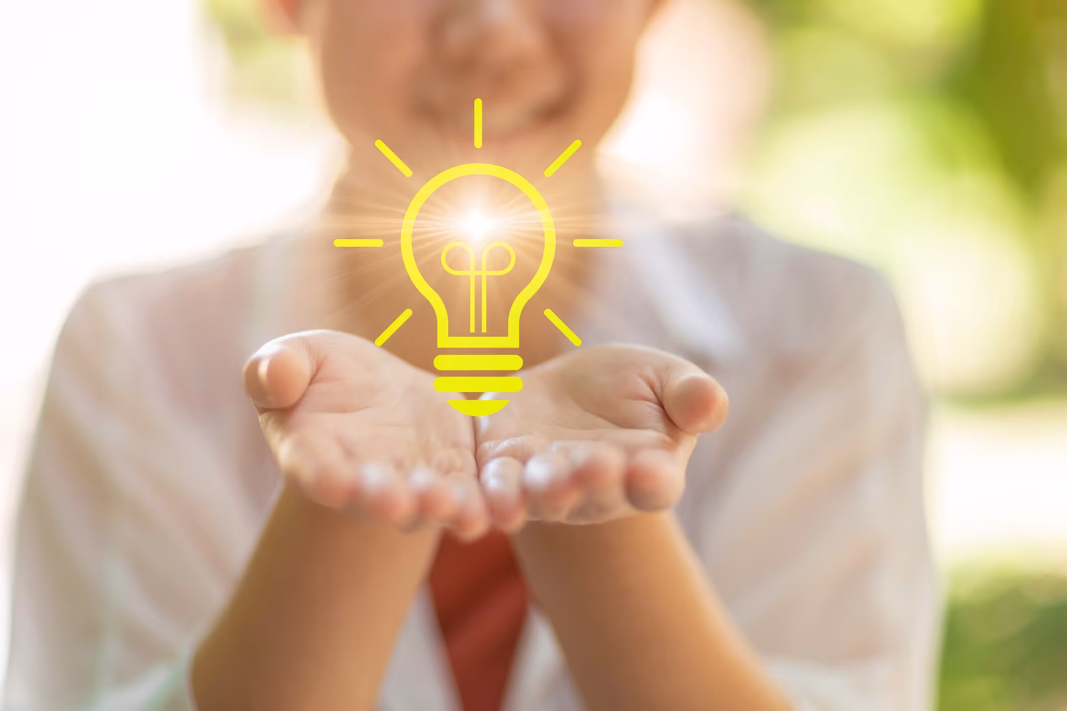 Дете държи стиснати длани с илюстрация на светеща крушка над тях.