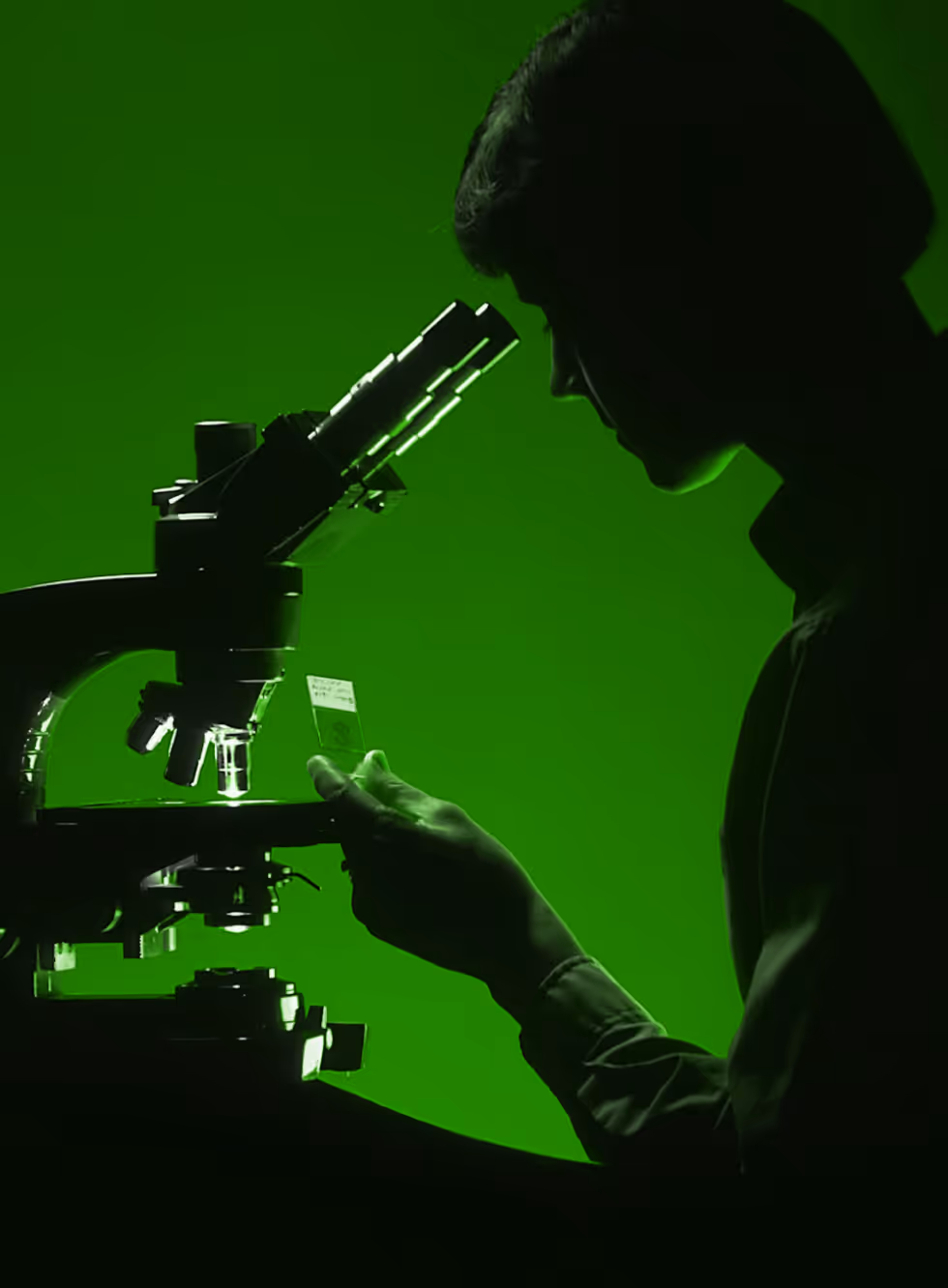 A person seeing through a microscope with green background