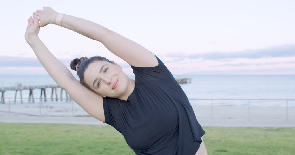 Leah stretching part of BARE Lean workout with beach and jetty in background