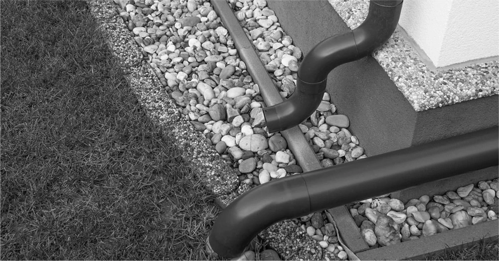 Black-and-white photo of residential drainage system along pathway