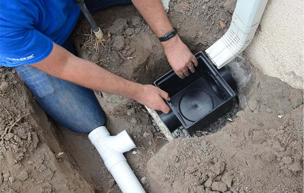 Contractor installing drainage box connected to gutter downspout