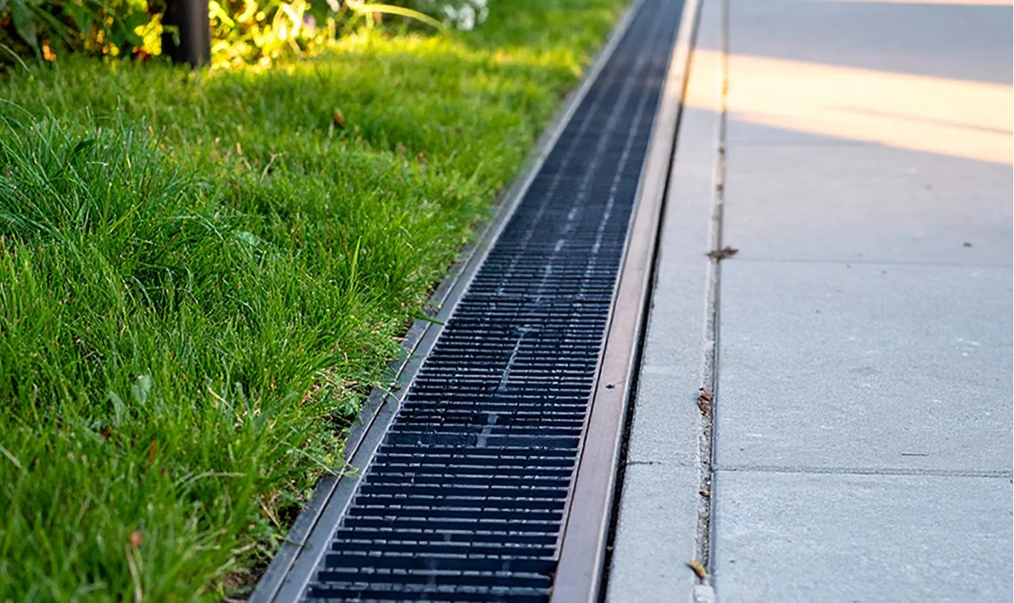Linear trench drain along pavement edge for stormwater collection