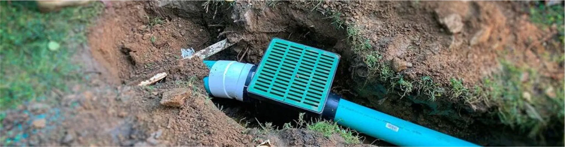 Green plastic catch basin connected to underground drain pipe