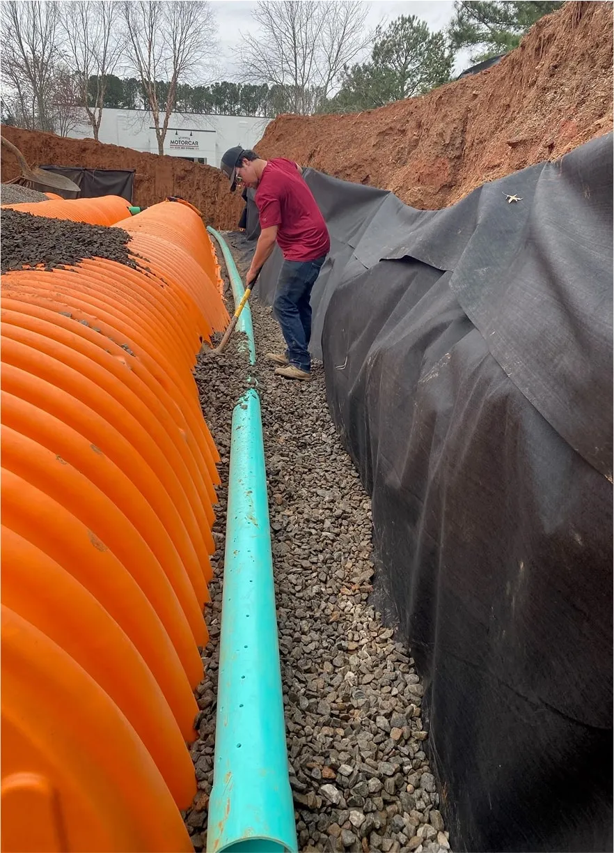 Construction crew connecting corrugated stormwater pipes in trench