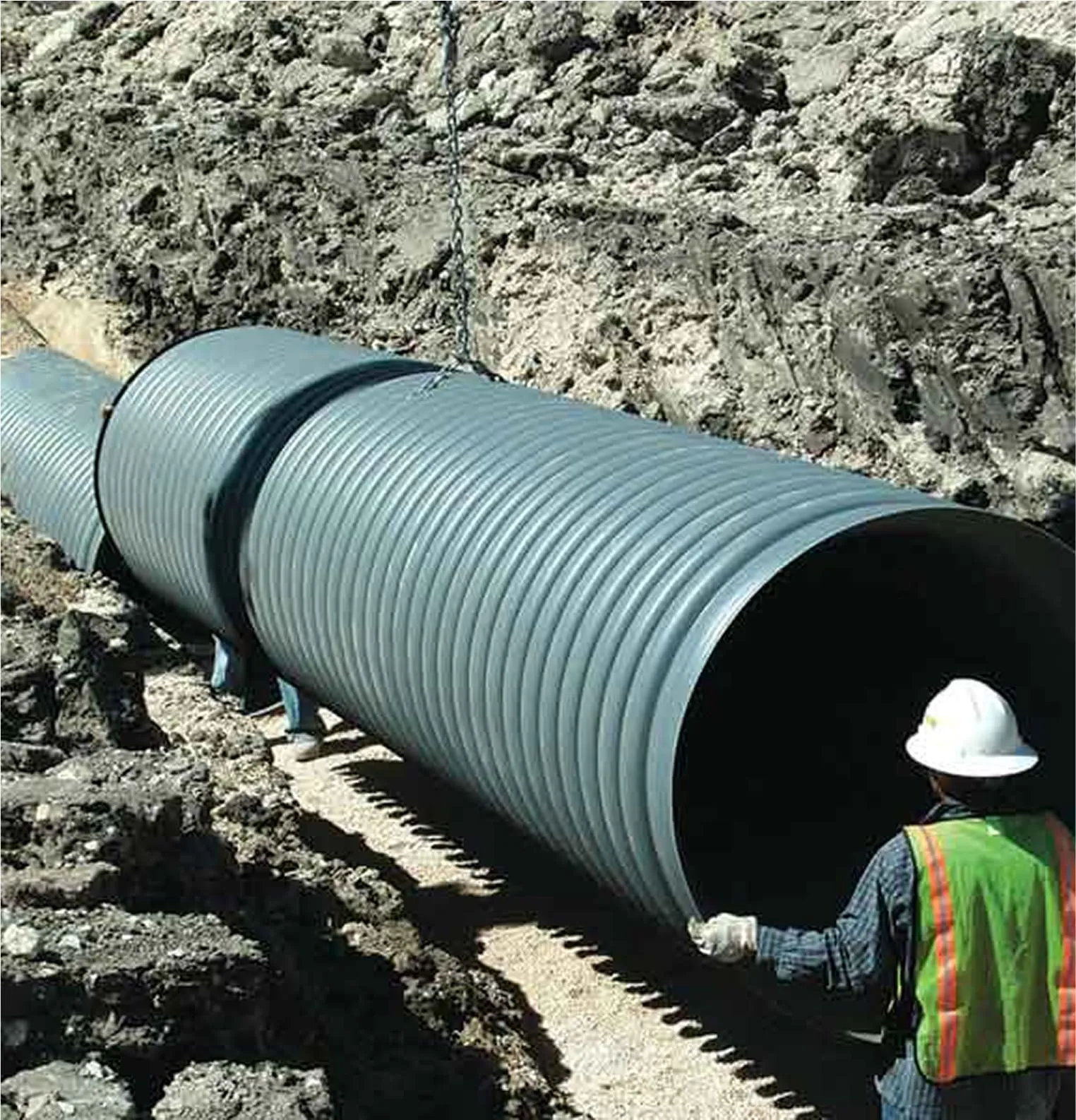 Worker installing large underground stormwater pipe system