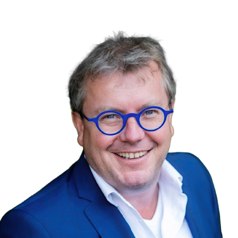 Man met grijzend haar en blauwe bril glimlachend, gekleed in een blauw jasje en witte blouse.