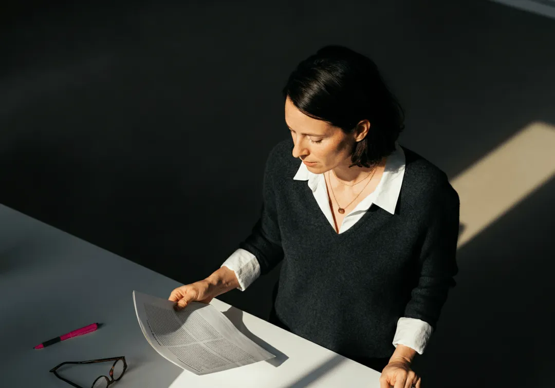 A woman sitting at a table with a piece of paper in front of her.
