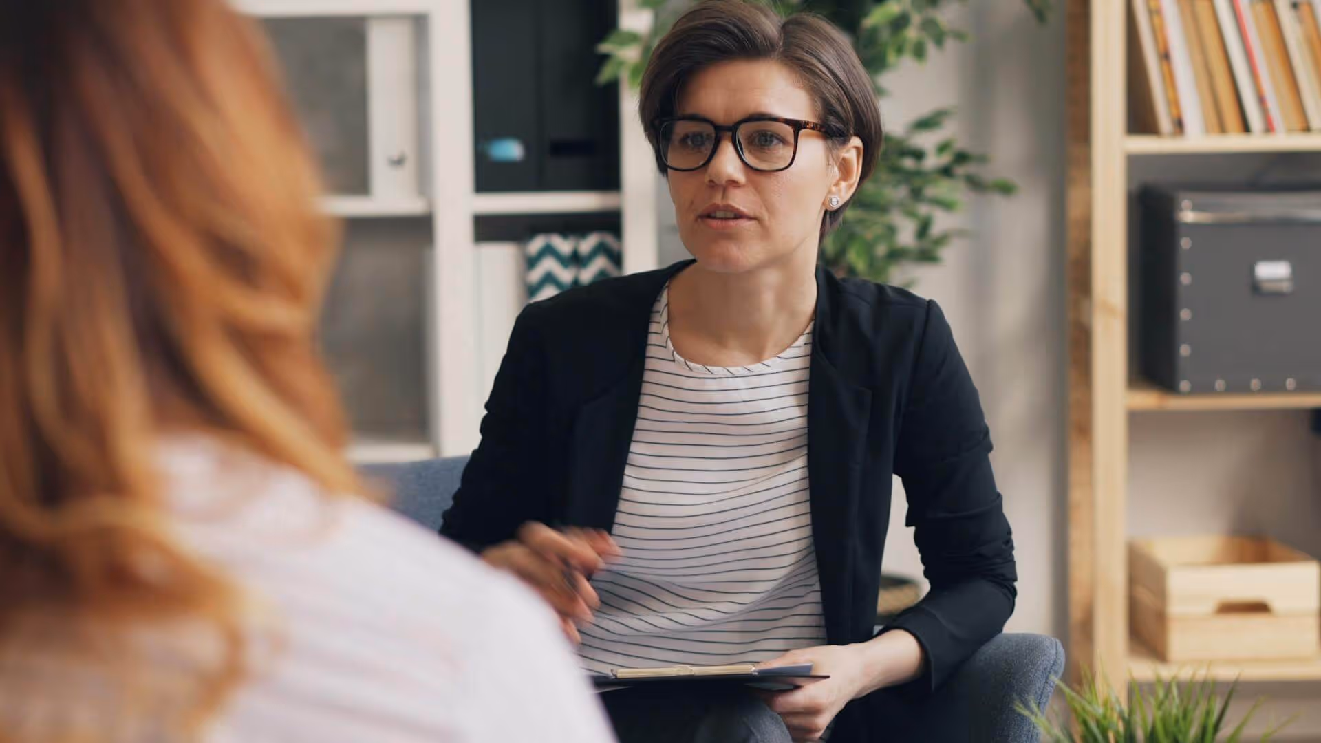 A woman wearing glasses and a black jacket.