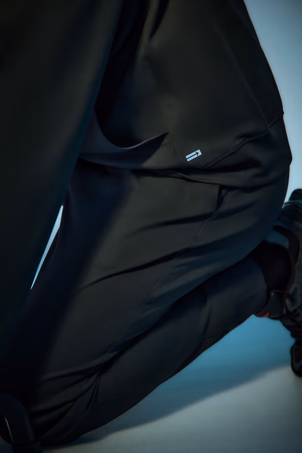 Close-up of a person wearing black athletic pants and black running shoes in a crouched position.