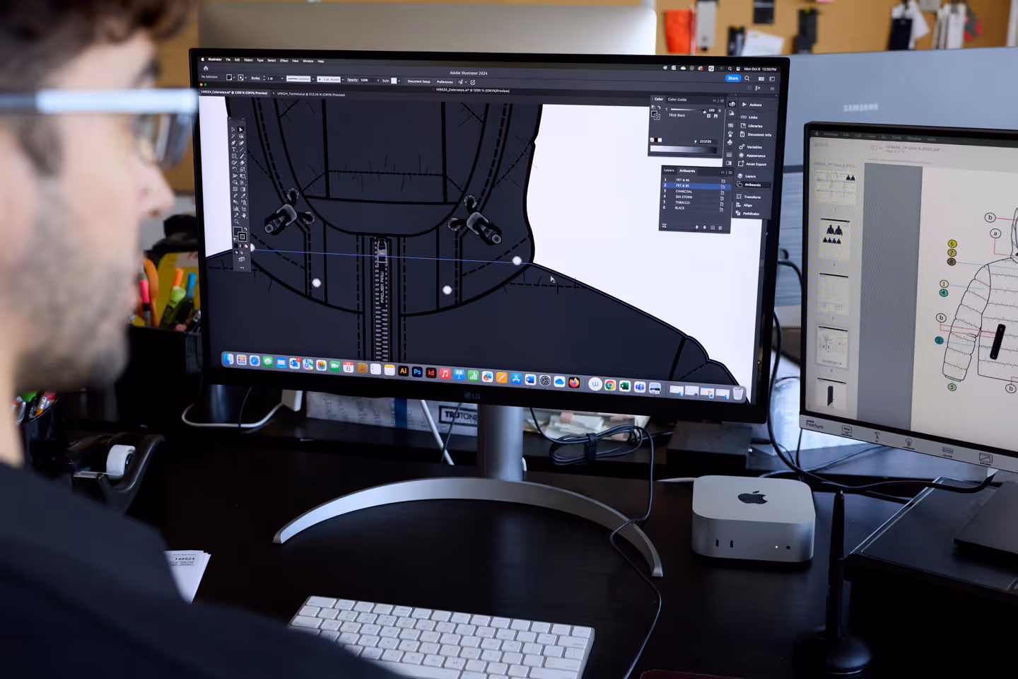 Person working on a computer with two monitors displaying jacket design and technical drawing in Adobe Illustrator.