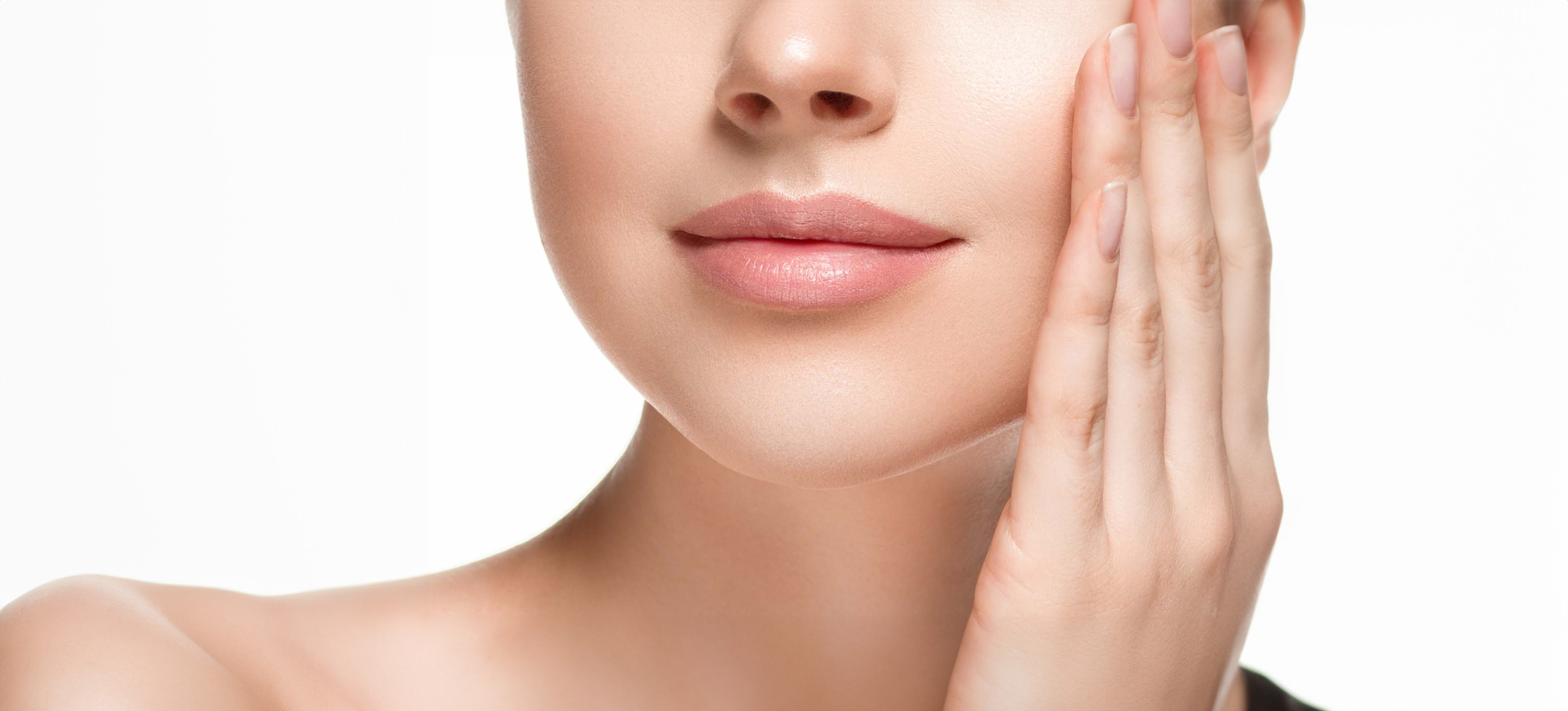 Dame som tar seg til kinnet og smiler lett etter fjerning av fillers i leppene.