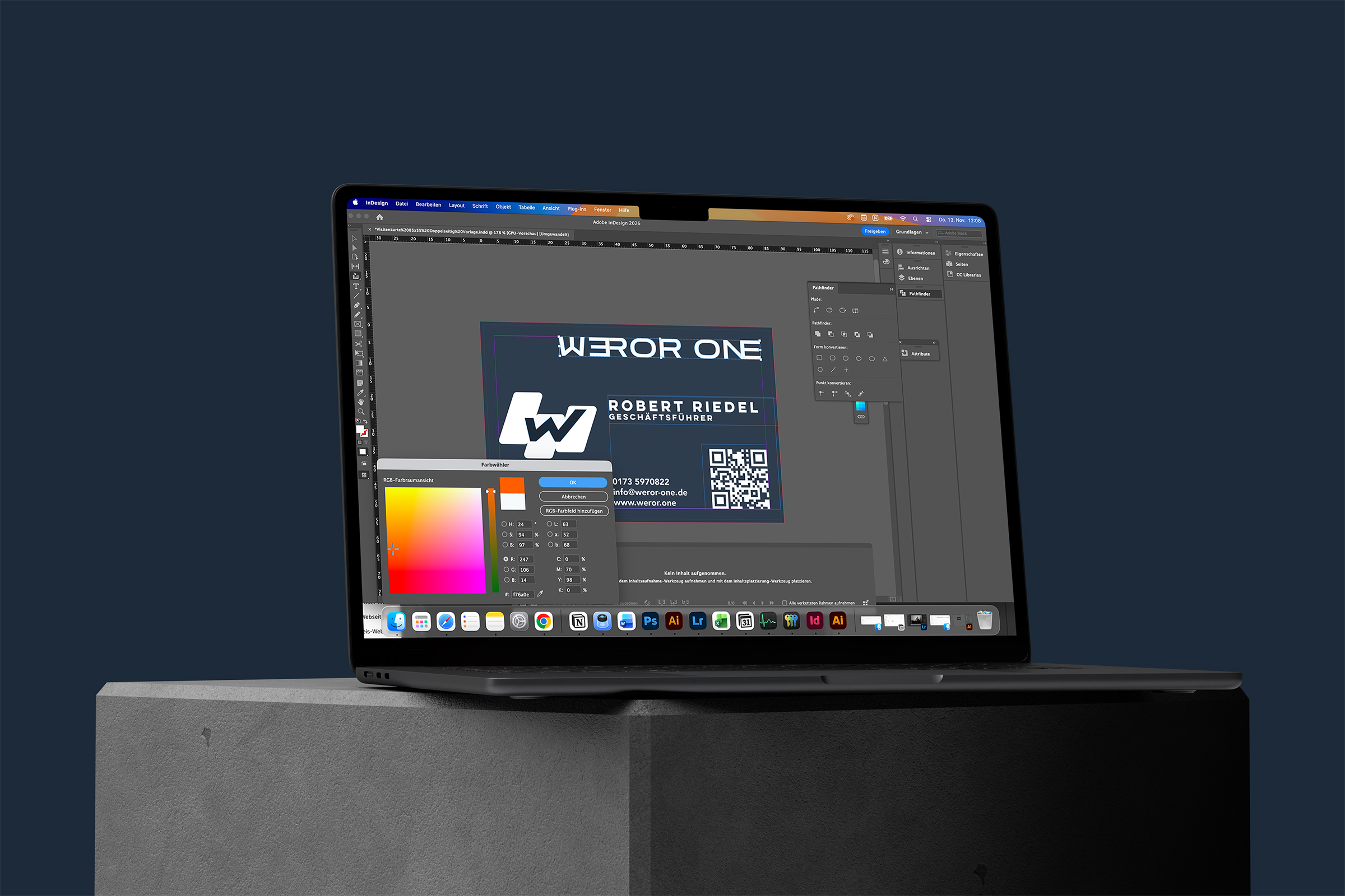 Laptop auf einem grauen Betonblock mit geöffnetem Adobe InDesign-Fenster, das eine Visitenkarte von Robert Riedel von WEROR ONE zeigt.
