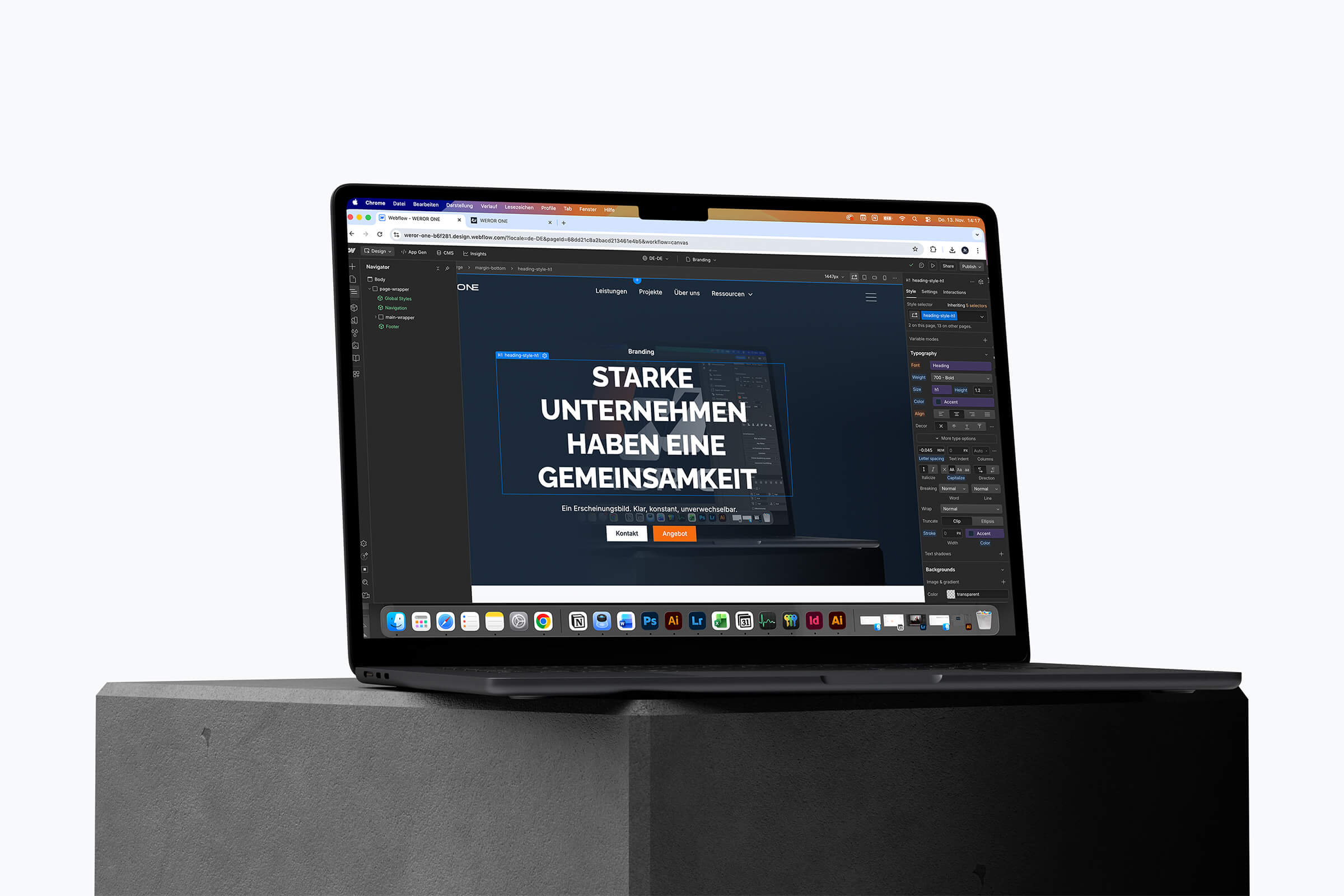 Aufgeklappter Laptop auf Zementblock zeigt eine Webdesign-Oberfläche mit dem Text 'Starke Unternehmen haben eine Gemeinsamkeit'.