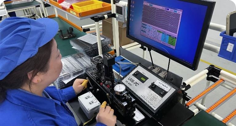 Person in blue uniform operating equipment in a factory setting.
