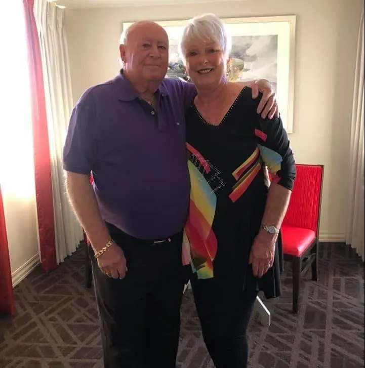 Older couple smiling together in home, wearing purple and black