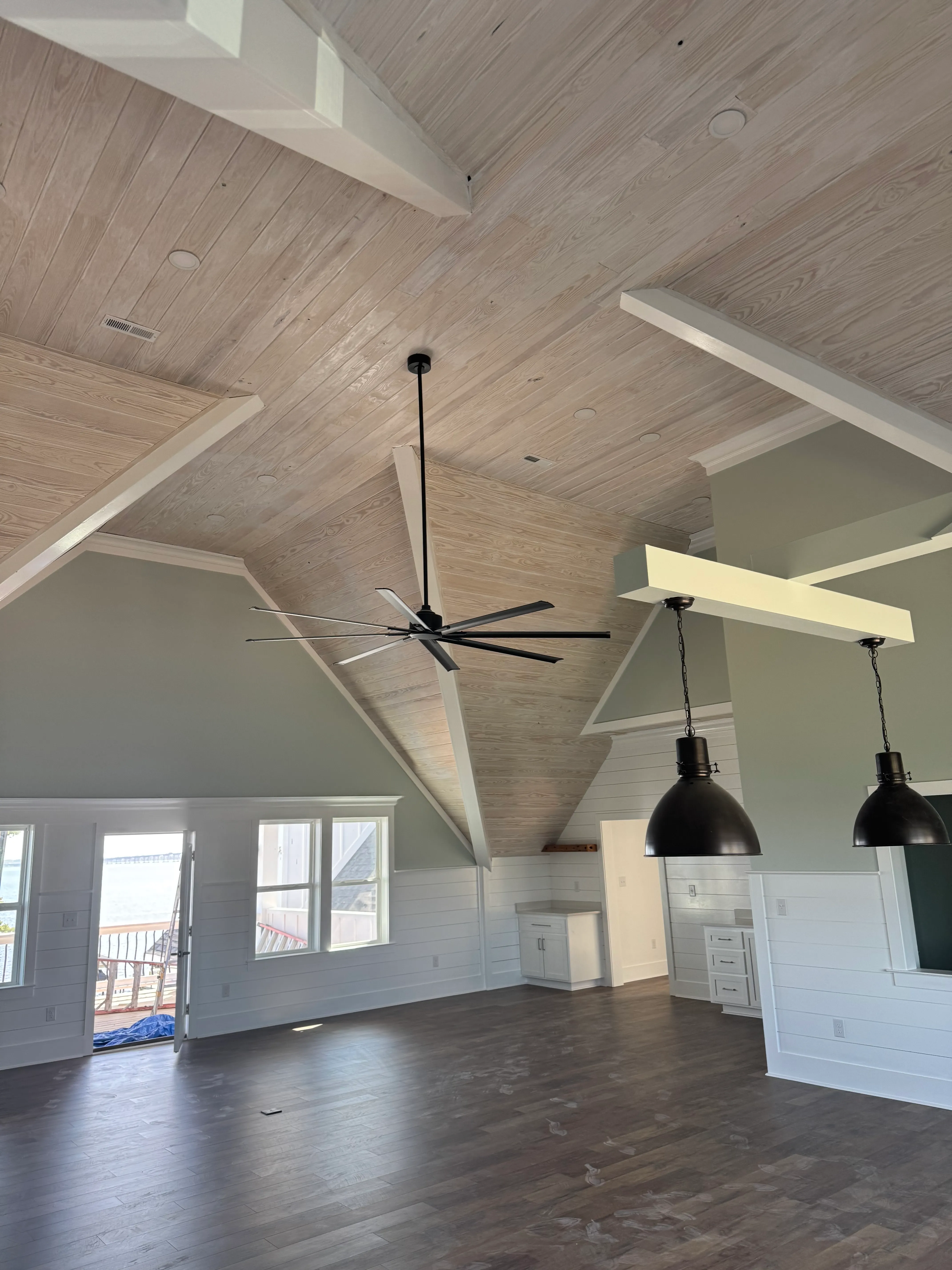 Modern open-concept room with wood ceiling, large fan, and pendant lights