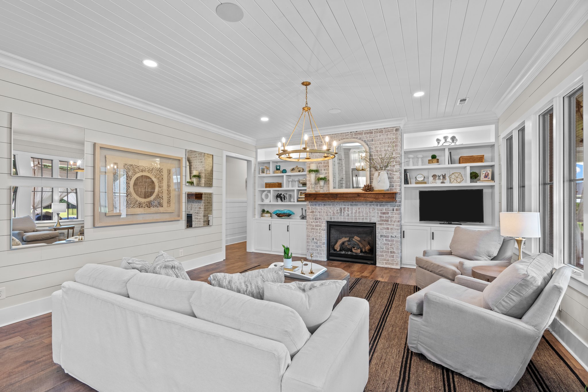 Bright, modern living room with white furniture, fireplace, and built-in shelves