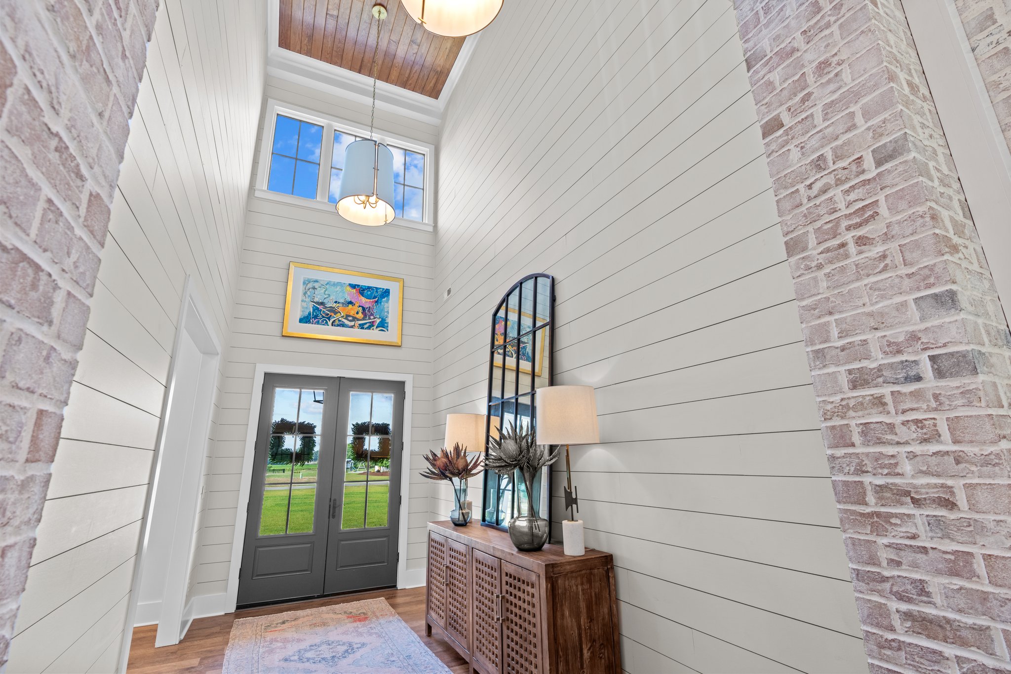 Bright entryway with high ceiling, gray doors, and artistic decor