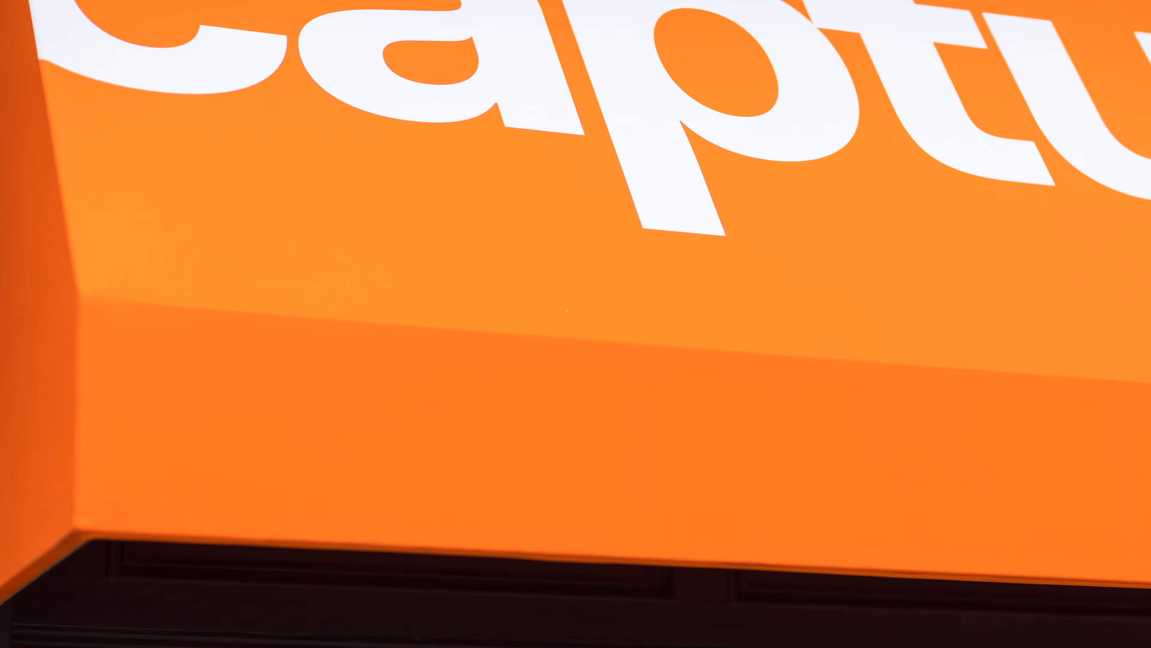 Close-up of an orange surface with partial white letters printed on it.