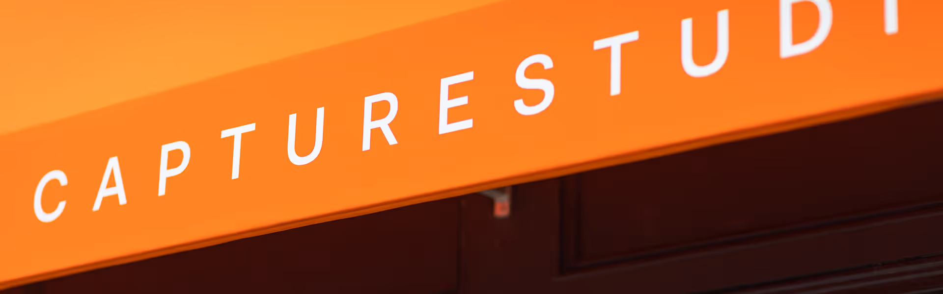 Orange awning with white letters spelling 'CAPTURE STUDI'.