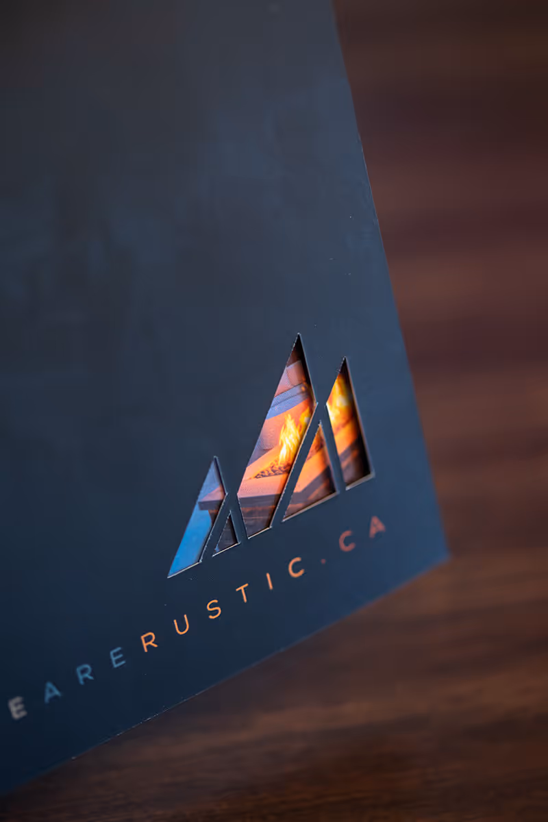 Close-up of a black card with triangular cutouts revealing a fire image beneath and the text 'EARRUSTIC.CA' below.