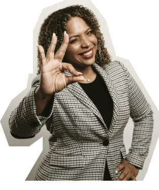 Two women sitting together at a law firm coaching event, smiling and posing for the camera. Both are wearing glasses, with one woman in a striped shirt and the other in a denim jacket. They are sitting at a table with law books and a phone visible in front of them. This image emphasizes the value of networking and collaboration in coaching for small law firm management and growth.