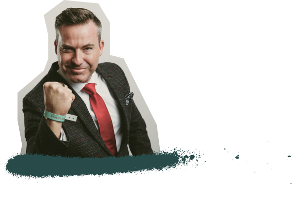 Two women smiling at the camera at a law firm coaching event, holding coffee cups. One woman is wearing glasses, a black scarf, and a conference badge, while the other is dressed in a gray jacket with a conference badge that reads ‘Carolyn.’