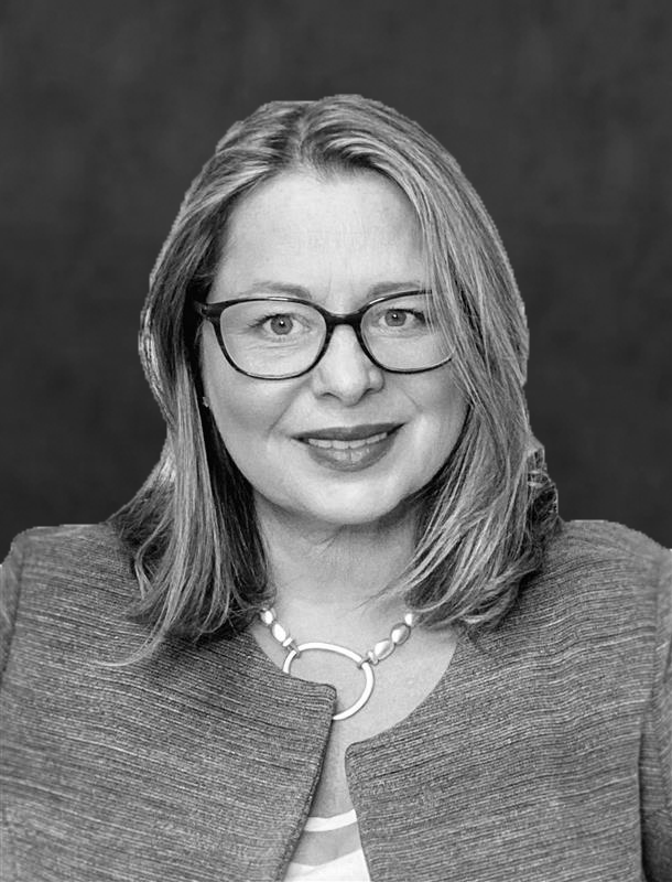 Headshot of Tania Music, Advisor & Special Counsel to the CEO at How to Manage a Small Law Firm, wearing a sweater vest and white button up smiling.