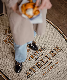 A person wearing black shoes and holding a bag of fries.
