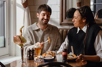 Two people sitting in the restaurant eating fries