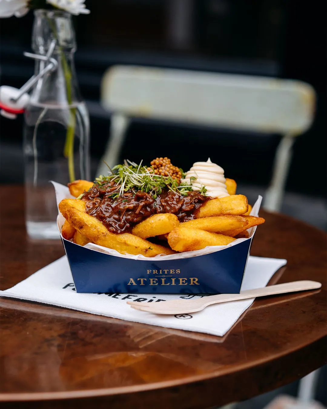 A box of fries with a white sauce on top.