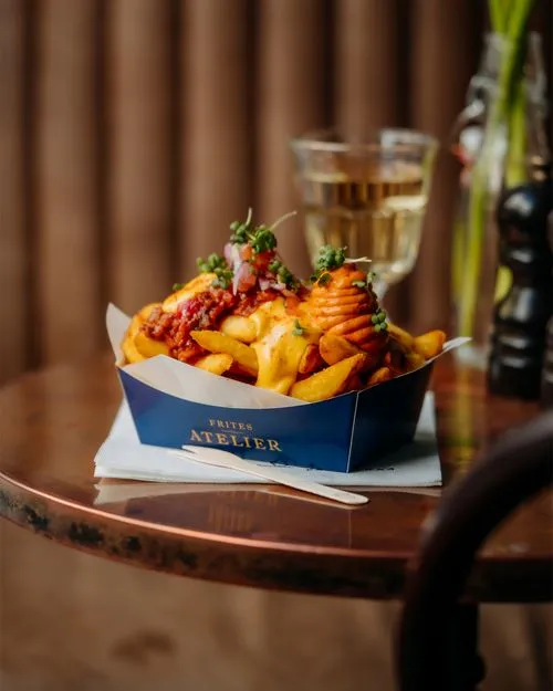 A box of fries with a glass of wine on a table.