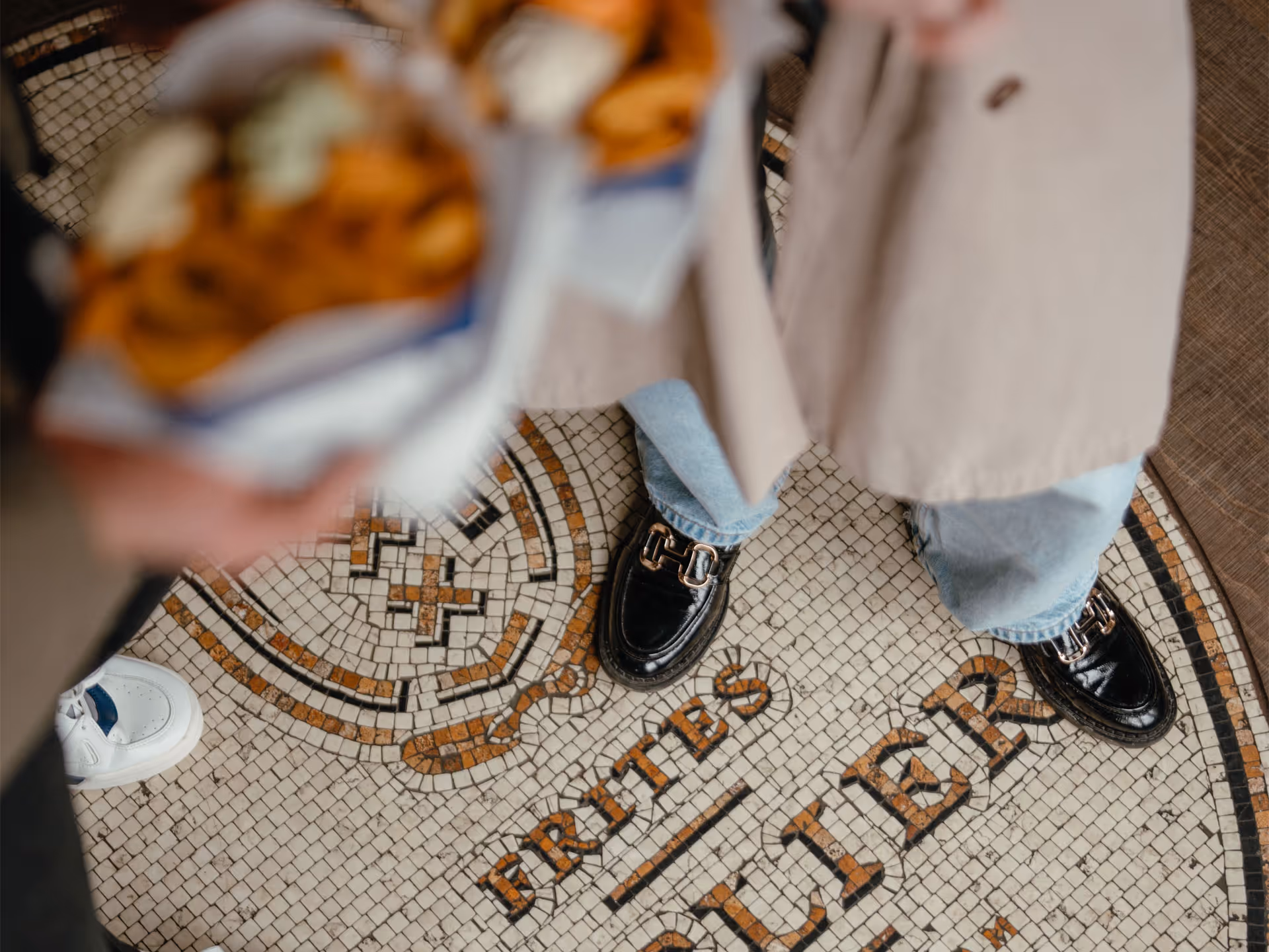 A person wearing black shoes and holding a bag of fries.