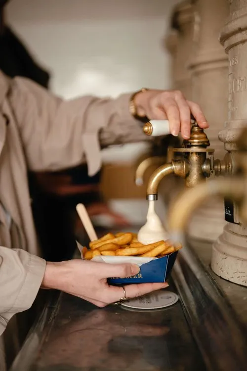 A woman putting sauce on her frites