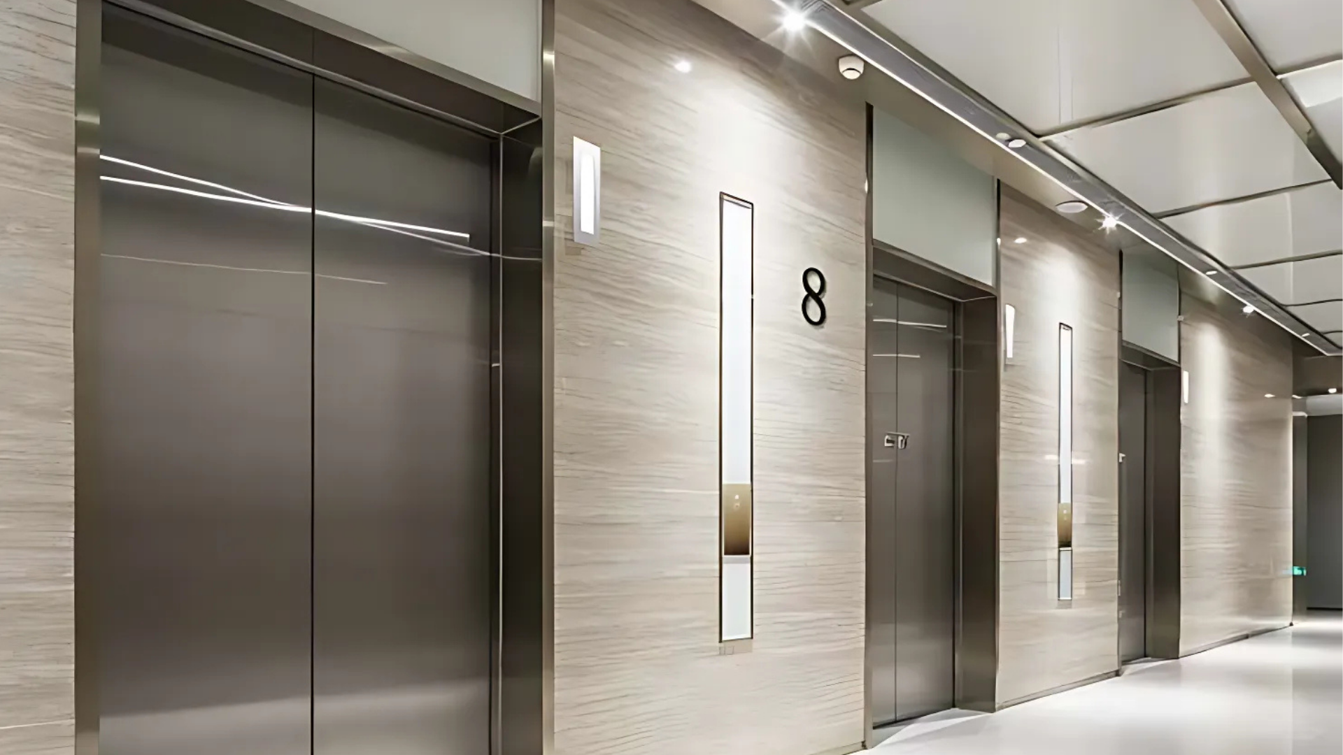 Modern elevator lobby with three closed steel elevator doors and the number 8 on the wall.