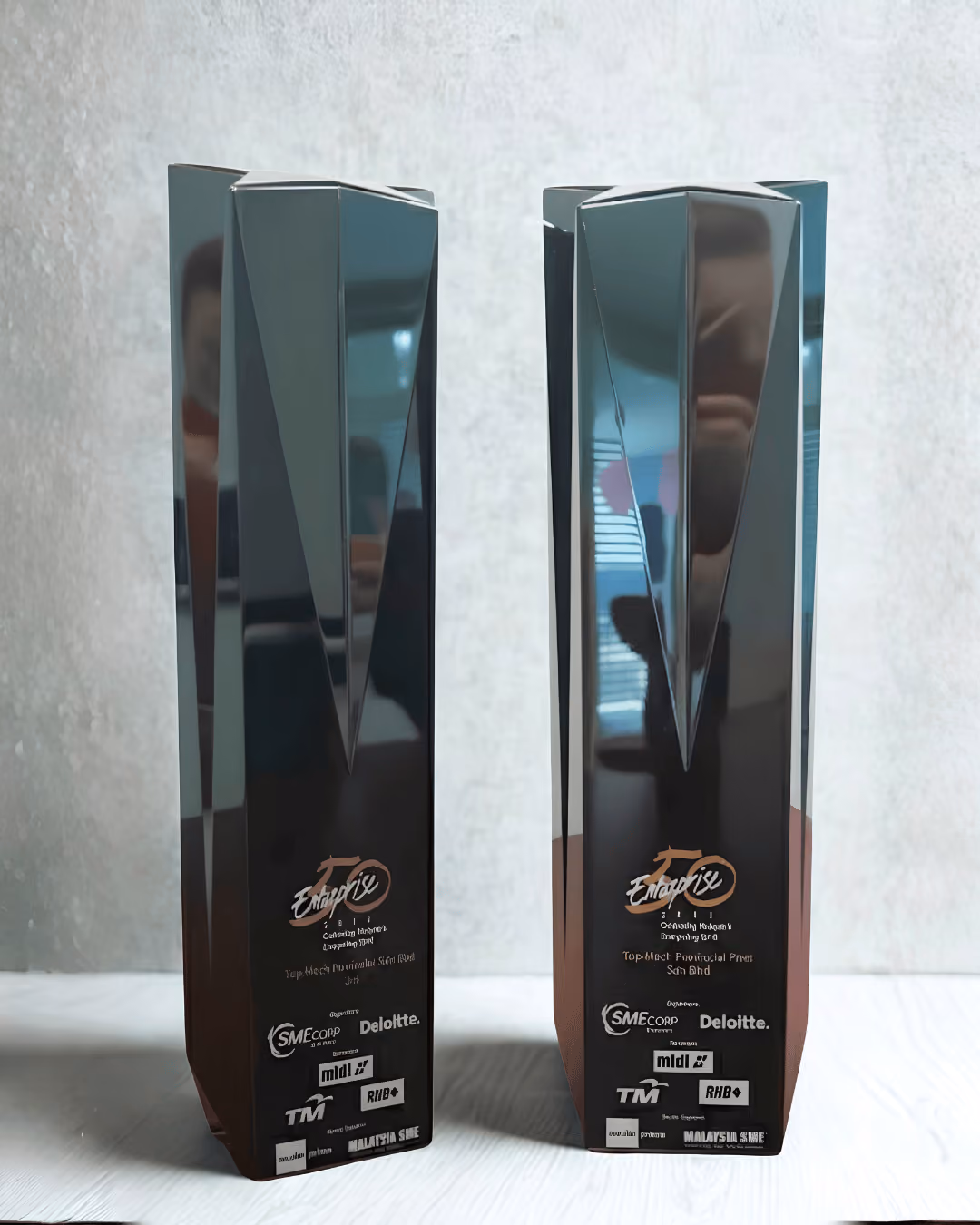 Two glossy black Enterprise 50 Awards trophies with logos and text on a white surface.