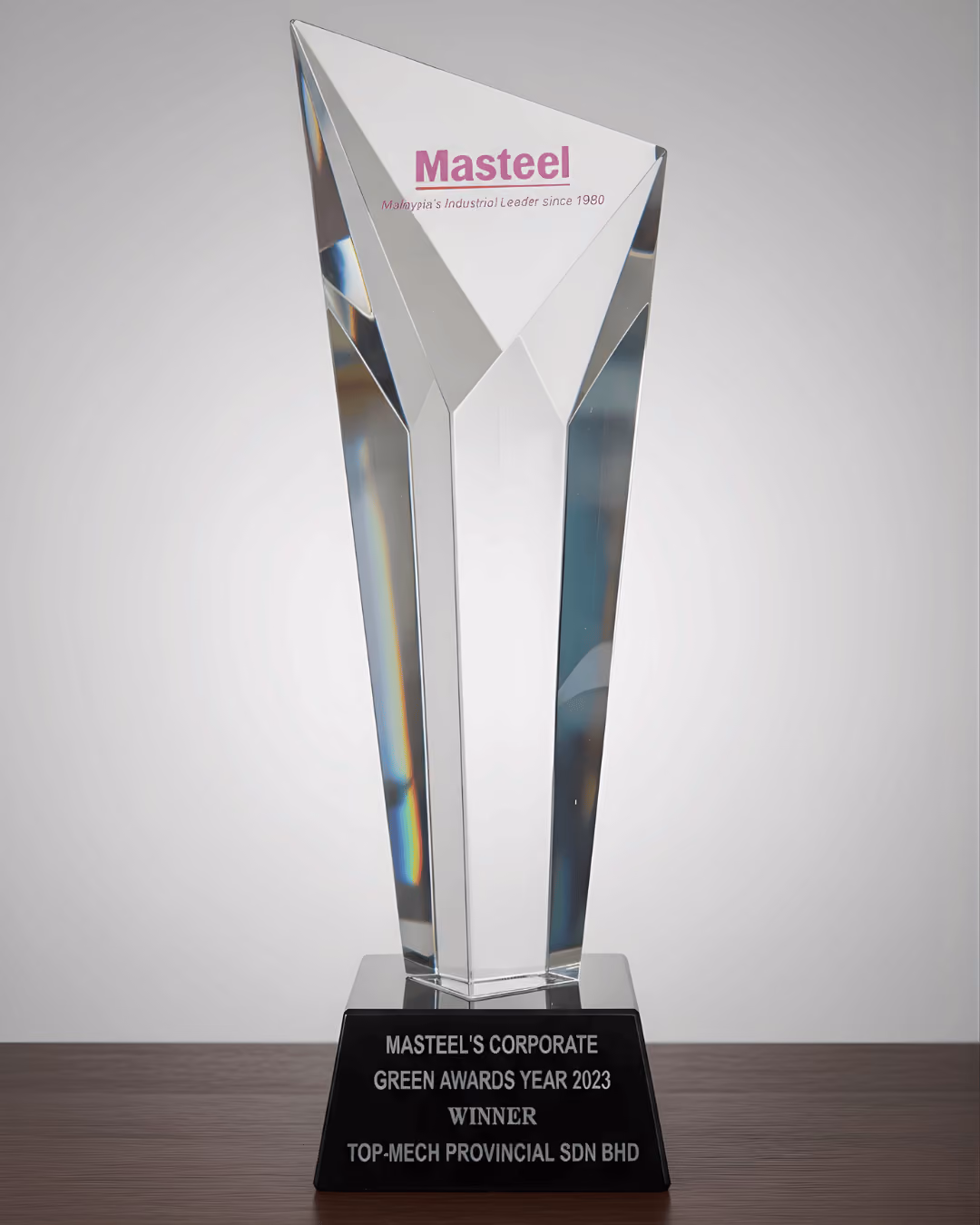 Clear glass award trophy on black base for Masteel's Corporate Green Awards 2023 winner.