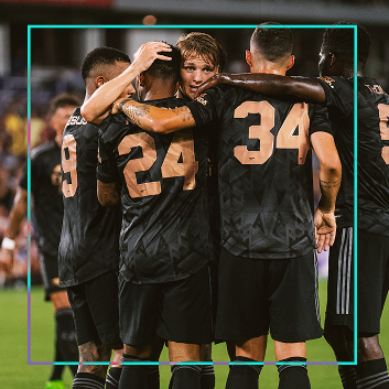 Group of soccer players huddled in the middle of the pitch.