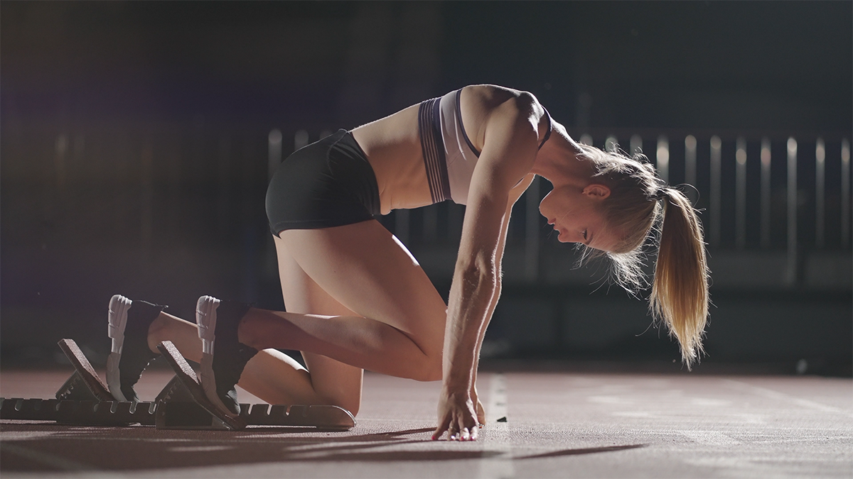 Image of a woman sprinter athlete in the blocks about to start a race.