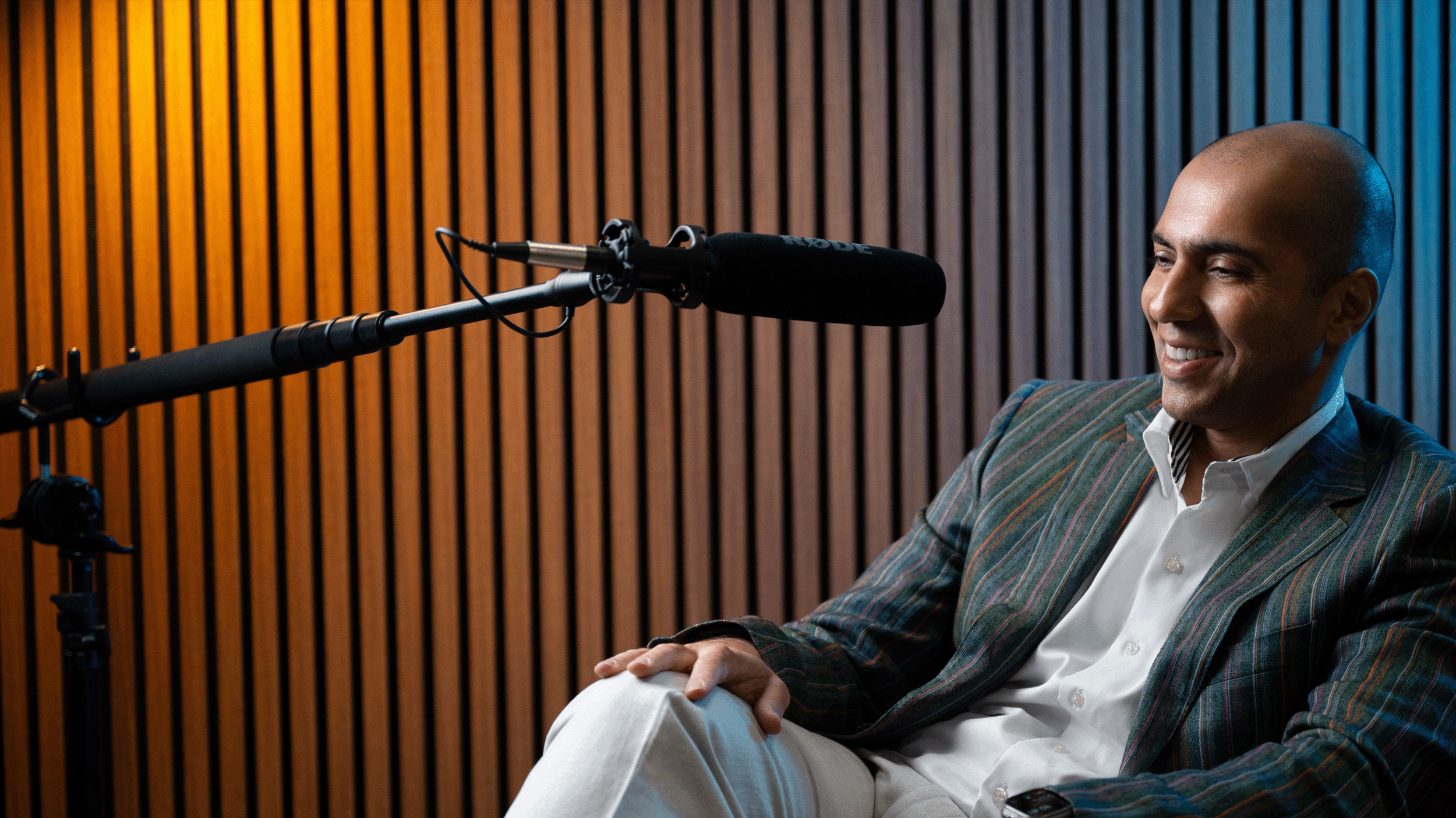 Photograph of man sitting, smiling in podcast studio.