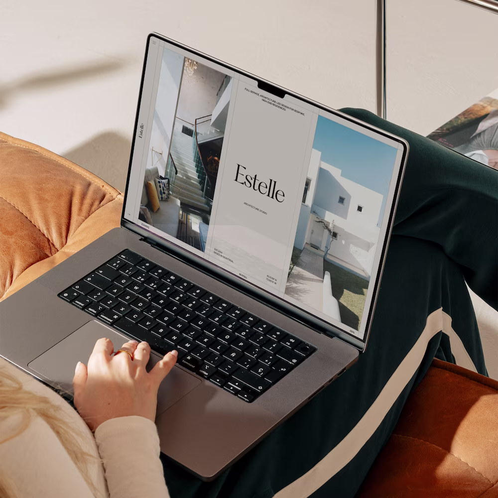 Person browsing the Estelle architectural studio website on a laptop, which showcases modern interior and exterior photography on a clean, light interface.