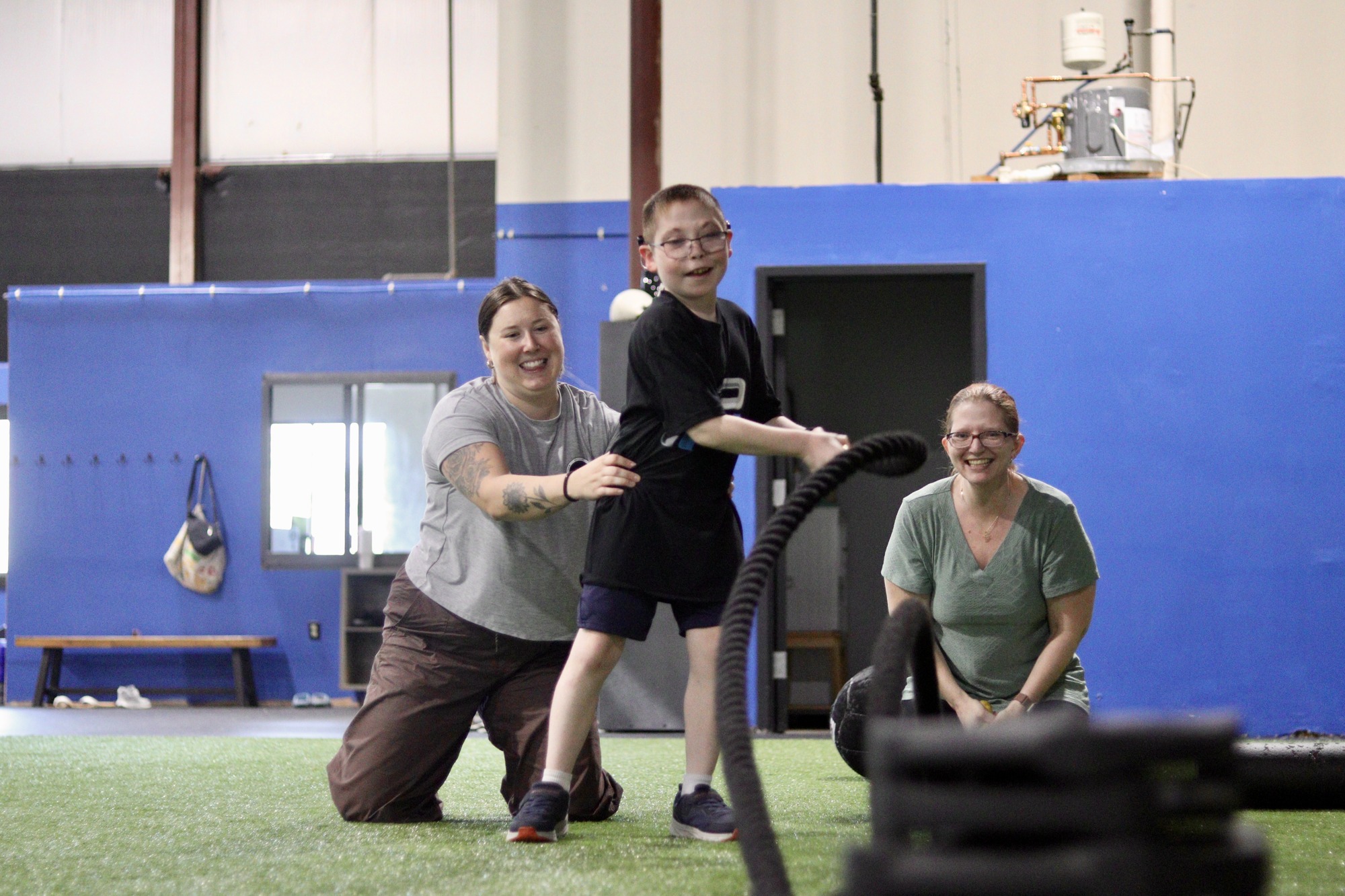 A KBP coach guiding a young athlete through battle rope training.