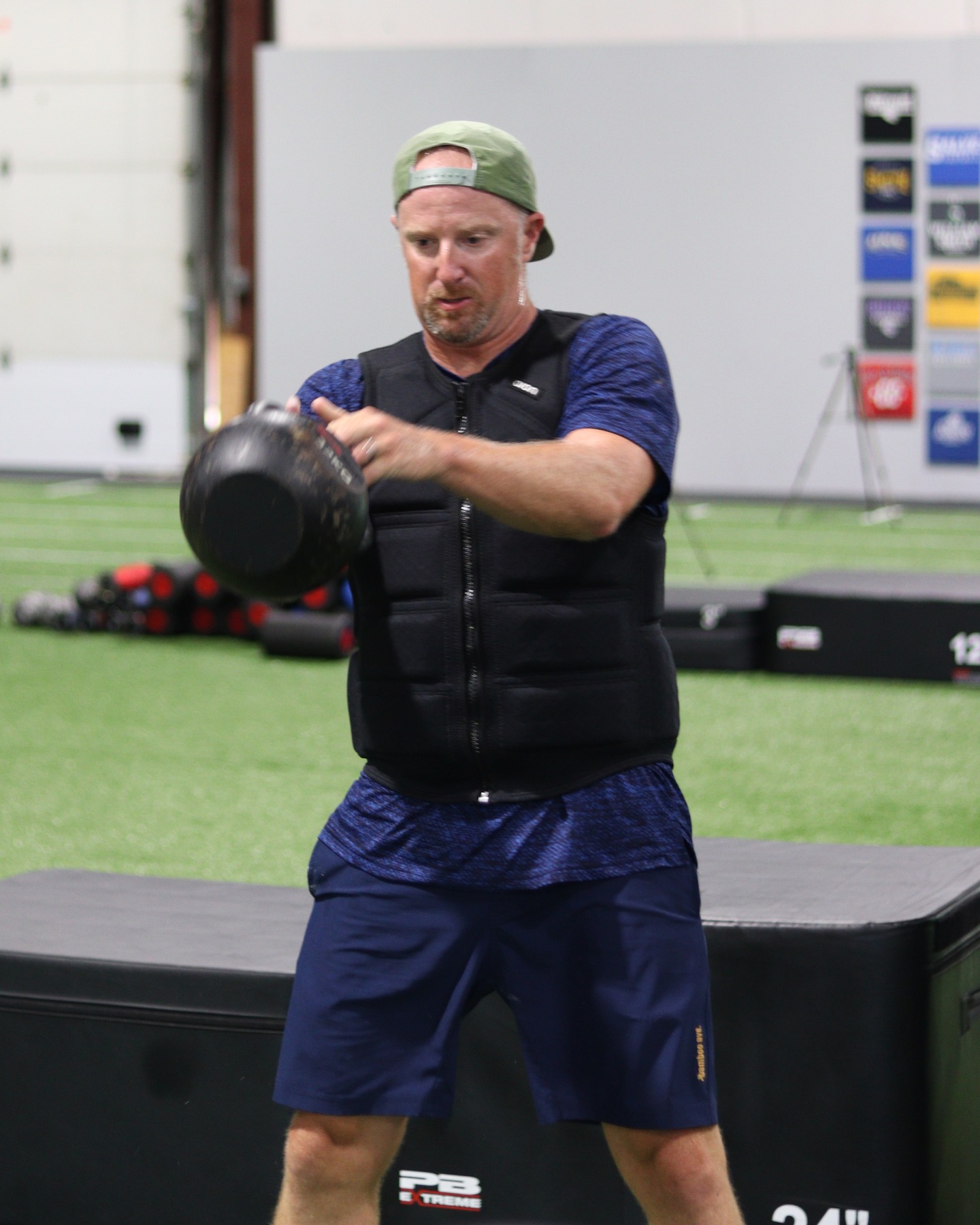 An adult KBP member training with a kettlebell and weighted vest in the new facility.